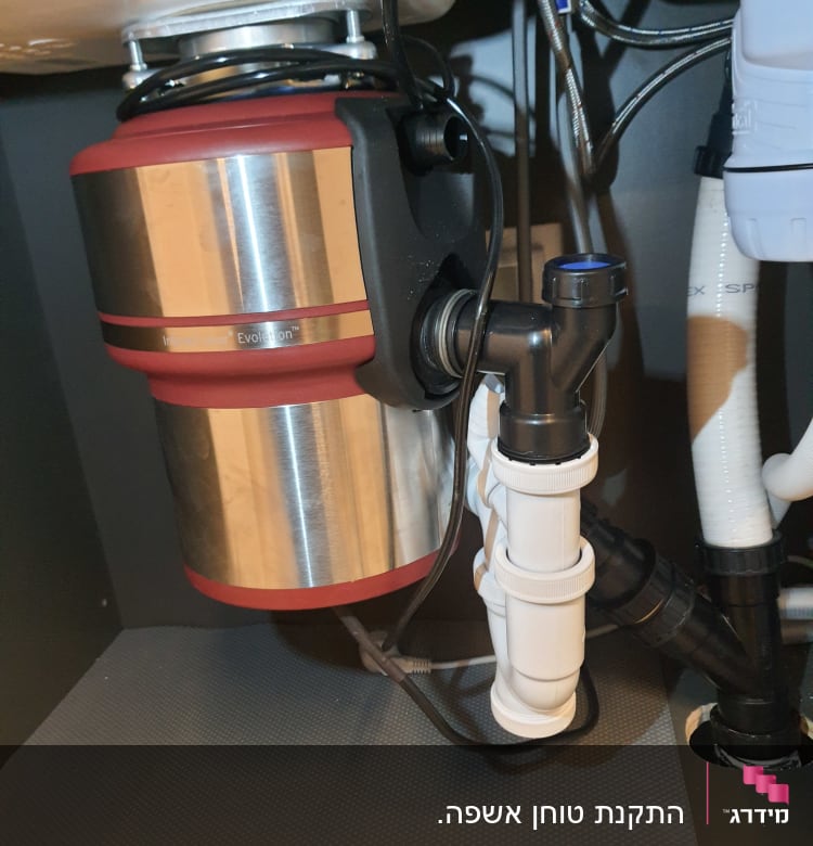 מכשיר טוחן אשפה מתחת לכיור עם צינורות חיבור